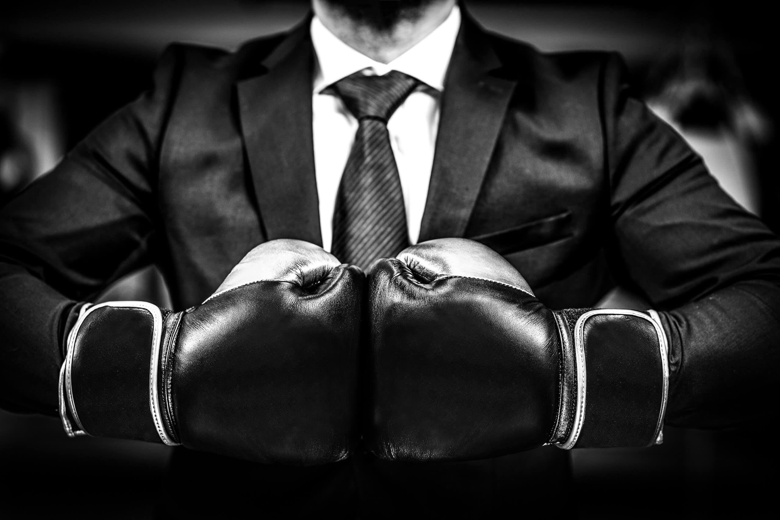 A person wearing a business suit and boxing gloves